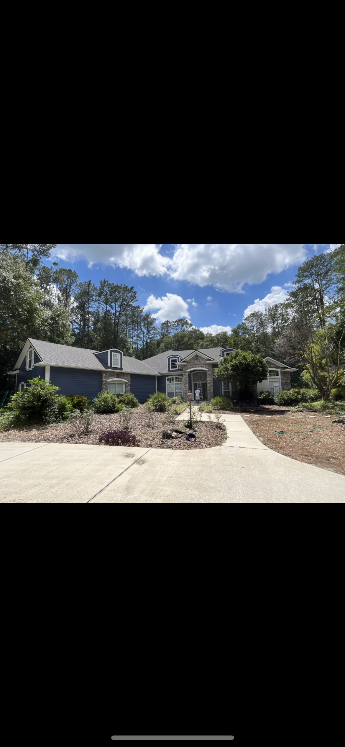 Custom home exterior painting navy blue with stone accents by HPC in Gainesville Florida