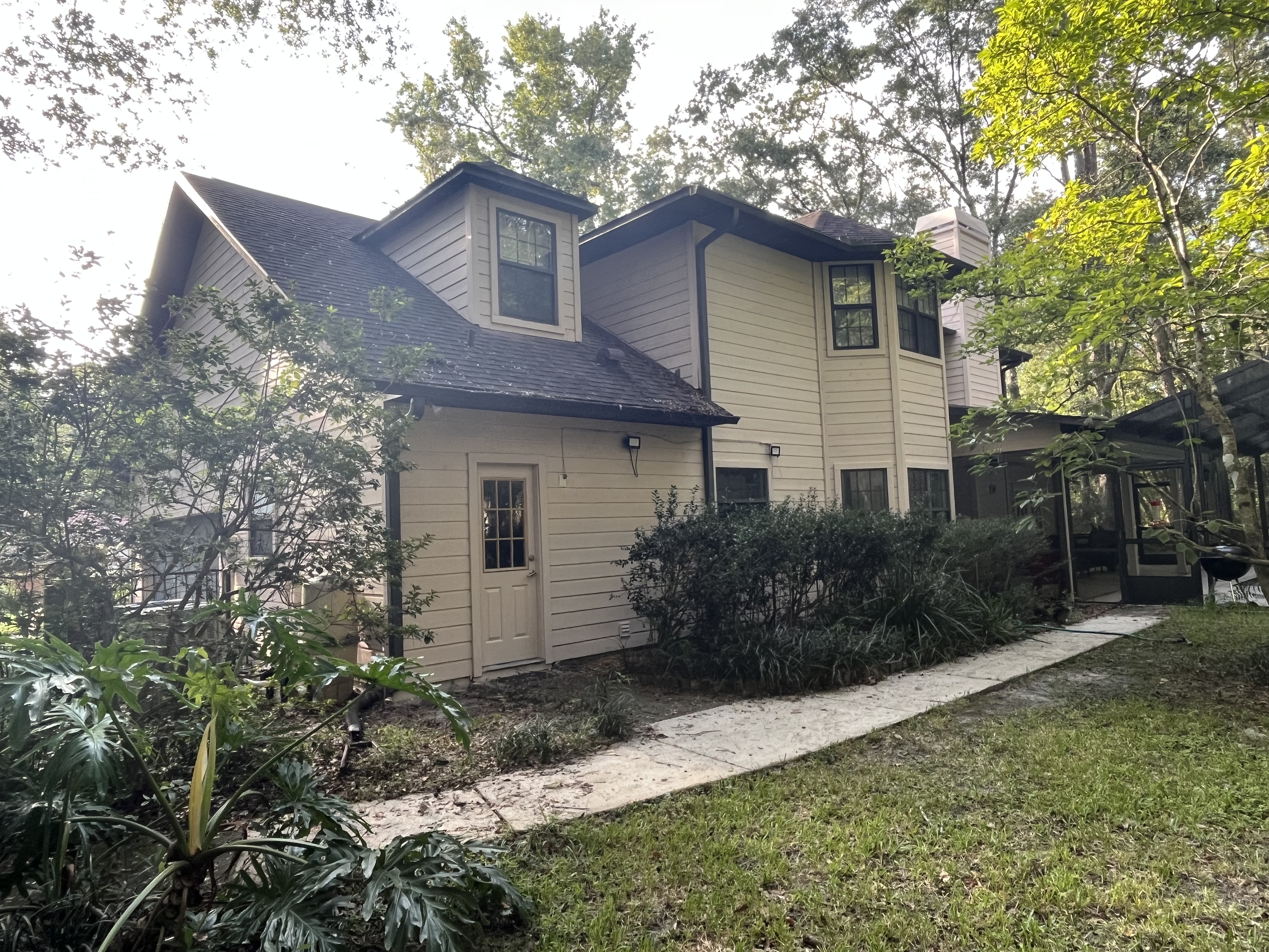 Wooded home exterior painting cream siding dark trim by HPC in Gainesville Florida